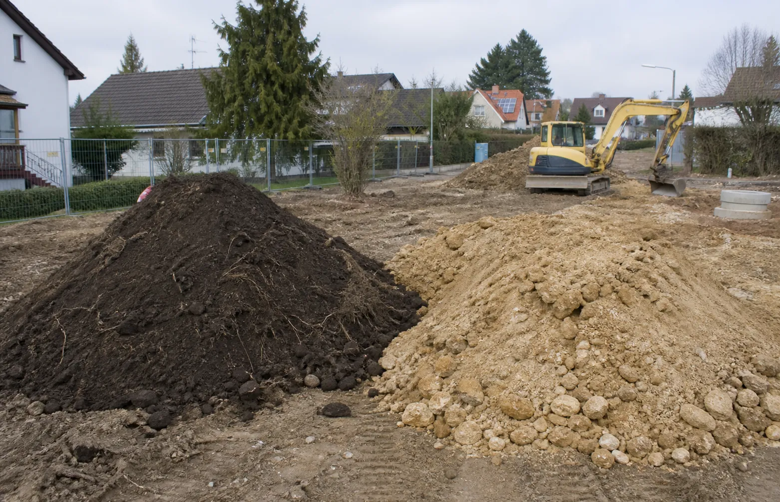 Getrennter Oberboden und Bodenaushub auf einer Baustelle vor Abtransport und Wiederverwendung