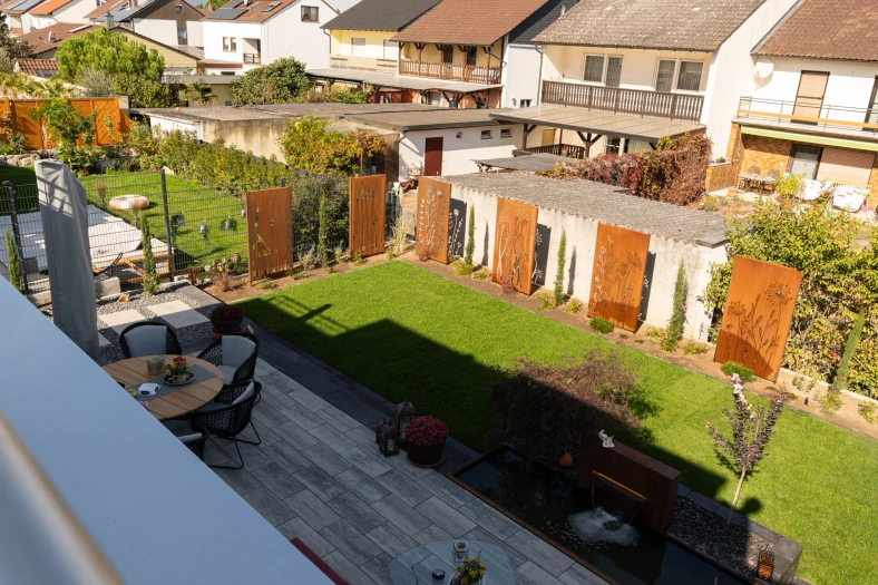 Gesamtansicht der fertigen Außenanlage mit Sitzbereich, Brunnen und Rasen