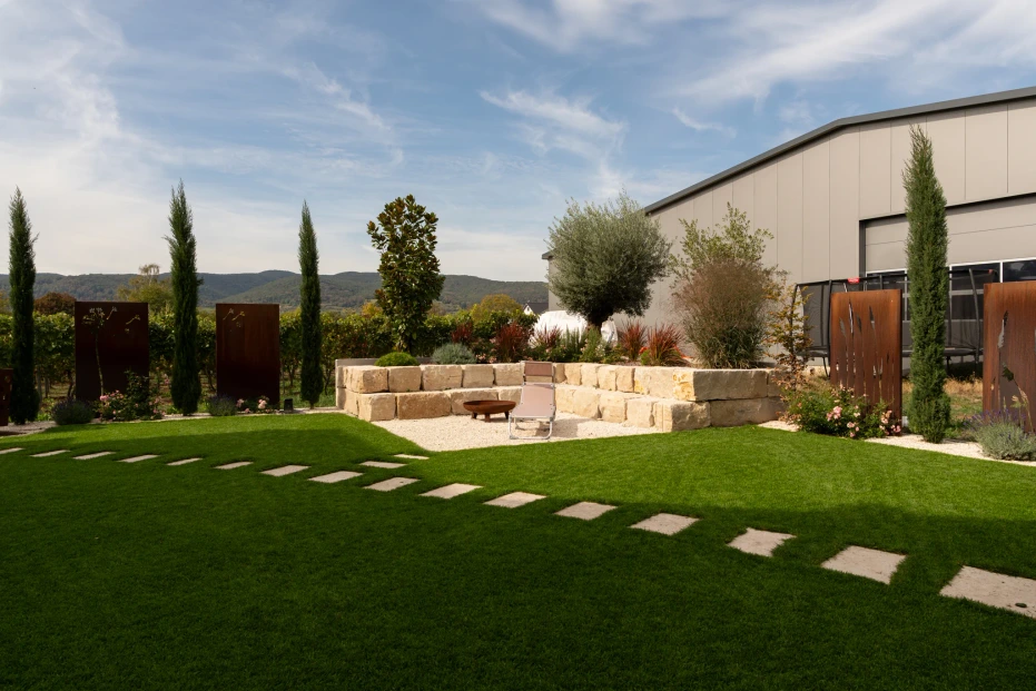 Garten in Niederkirchen mit Trittplatten im Rasen und einem von Natursteinmauern eingefassten Kiesplatz