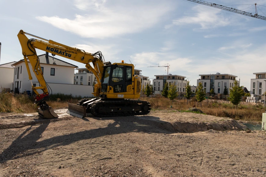 Seitliche Ansicht des ZuhauseBauen-Kettenbaggers auf dem Baugrundstück