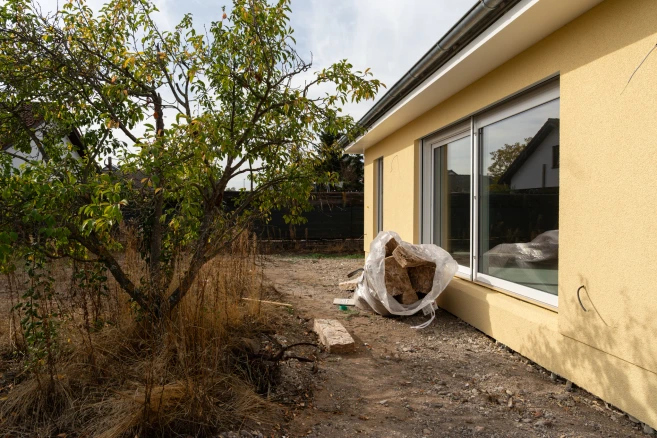 Seitlicher Blick auf die große Fensterfront mit Baum im Garten